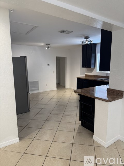 A kitchen area with a black refrigerator and a countertop.