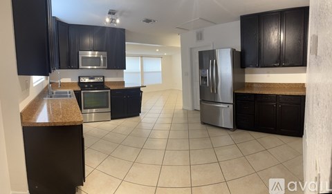 A kitchen with black cabinets and a tiled floor.