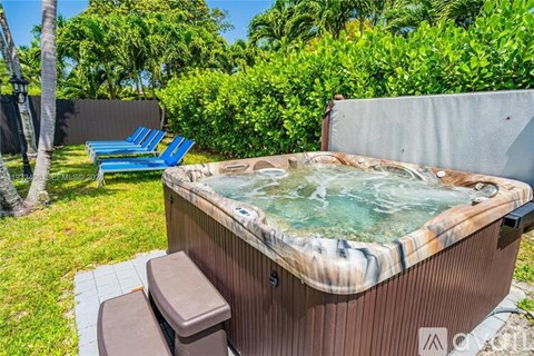 A hot tub is surrounded by a blue chair and a brown trash can.