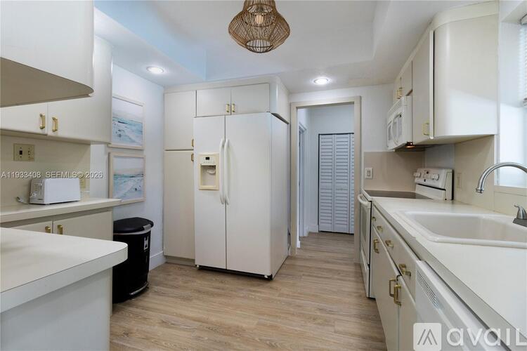 A kitchen with white cabinets and a white fridge.