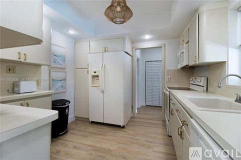 A kitchen with white cabinets and a white fridge.