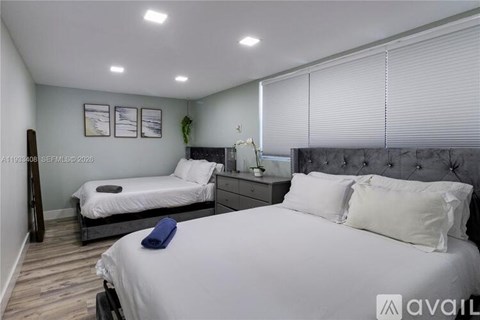 A bedroom with two beds and a nightstand.