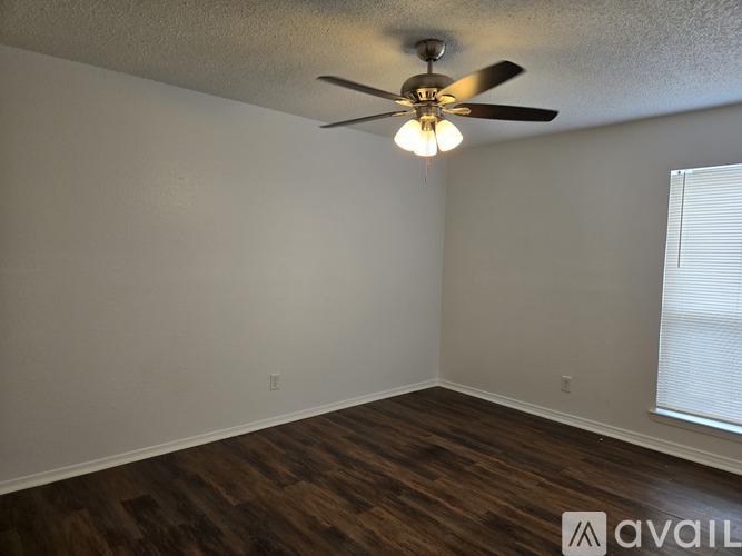 A room with a ceiling fan and wooden flooring.