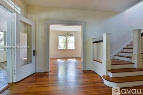A spacious hallway with a staircase and a chandelier.