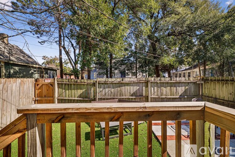 A wooden deck overlooks a backyard with a fence and trees.