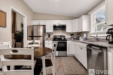 A kitchen with a table and chairs in front of a refrigerator and stove.
