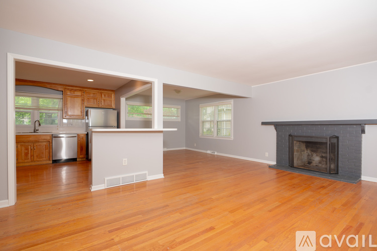 A large open living room with a fireplace and a kitchen area in the background.