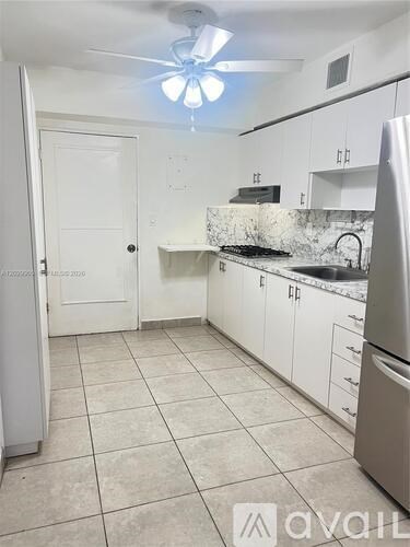 A kitchen with white cabinets and a marble backsplash.