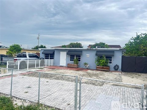 A house with a grey roof and a white fence in front.