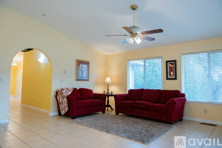 A living room with a red couch and a ceiling fan.