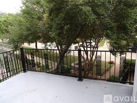 A balcony with a black railing and trees in the background.