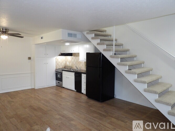 A kitchen with a refrigerator, stove, and oven is located under a staircase.