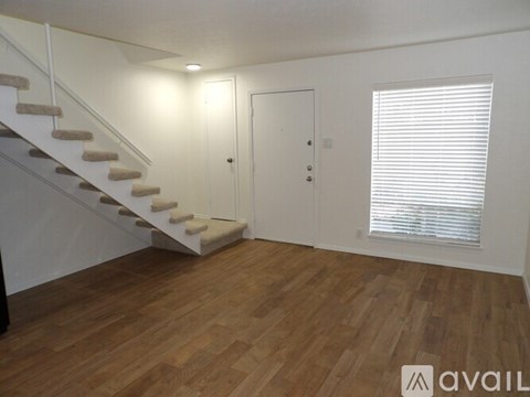 A room with wooden floors and a staircase leading to the upper level.