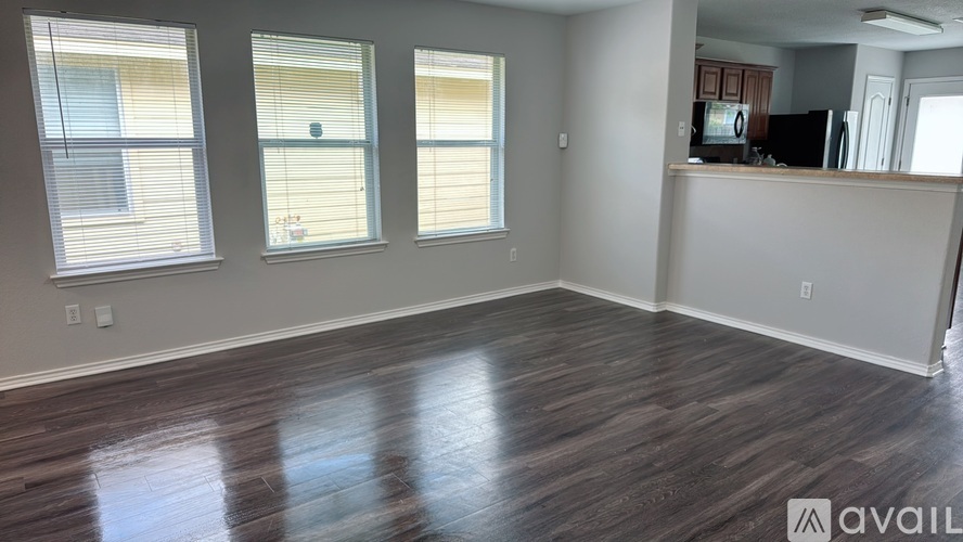 A spacious room with wooden floors and large windows.