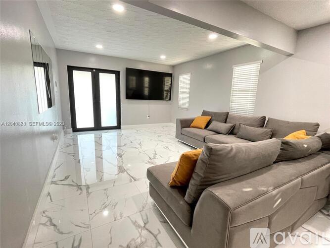 A living room with a grey couch and a marble floor.