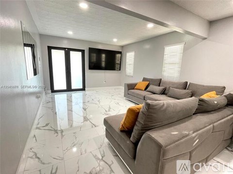 A living room with a grey couch and a marble floor.