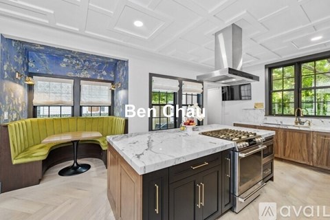 A modern kitchen with a large island and a green booth.
