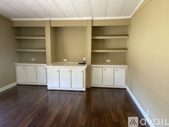 A room with wooden floors and white cabinets.