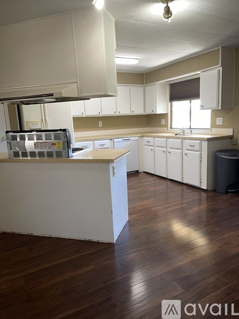 A kitchen with white cabinets and a wooden floor.