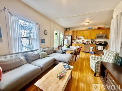 A living room with a couch, a table, and a kitchen in the background.
