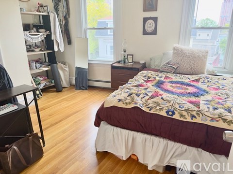 A bedroom with a bed, nightstand, and a window with a view of the city.
