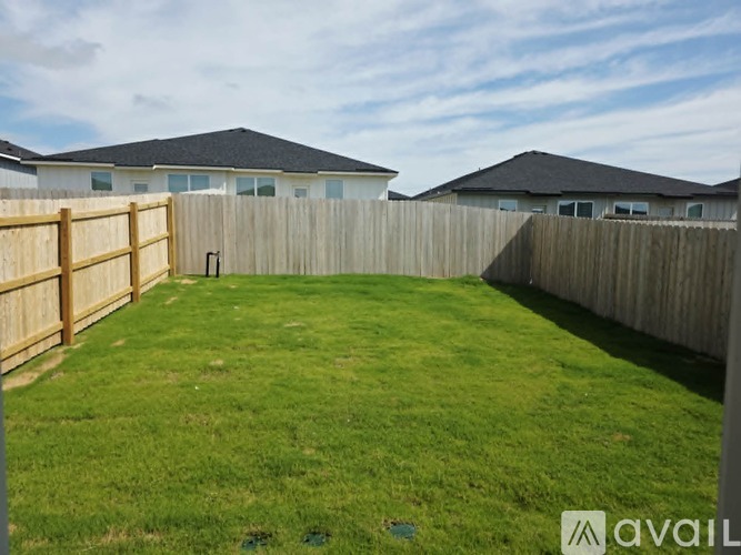 A backyard with a wooden fence and green grass.