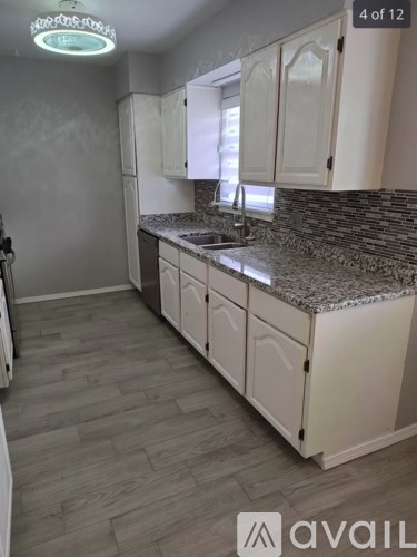 A kitchen with white cabinets and a granite countertop.