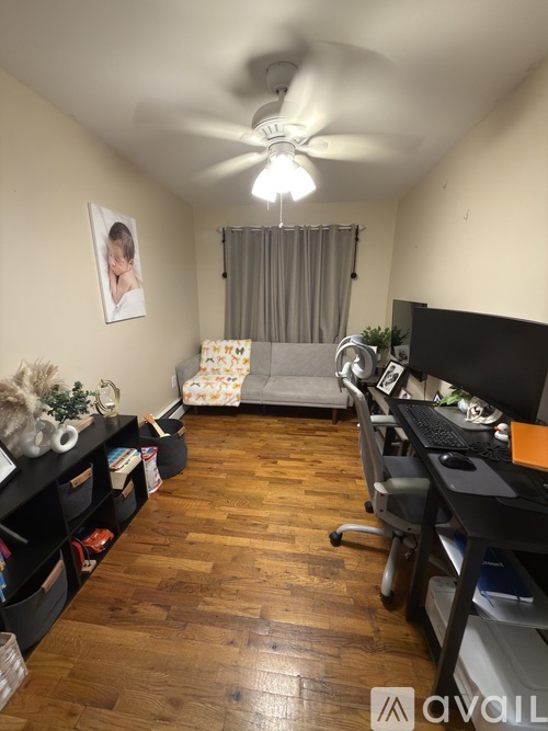 A room with a ceiling fan and a bed in the corner.
