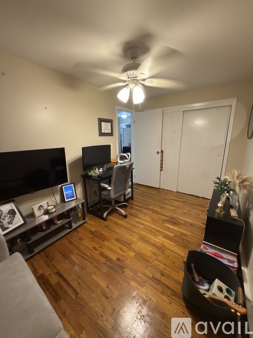 A living room with a television, a chair, and a ceiling fan.
