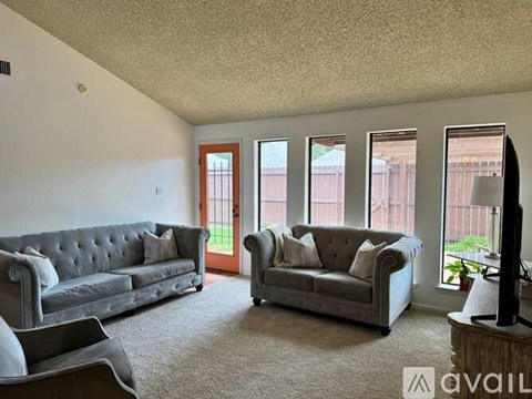 A living room with two grey couches and a television.