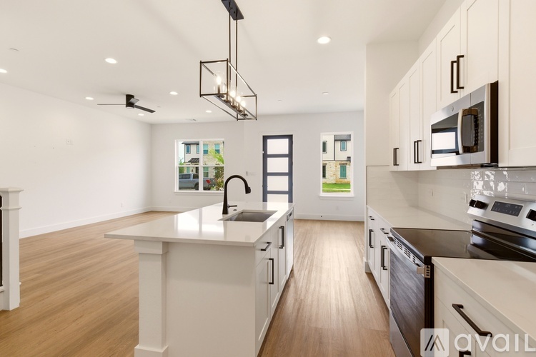 A modern kitchen with wooden floors and white cabinetry.