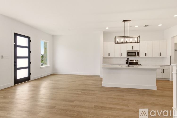 A spacious kitchen with white cabinets and a wooden floor.