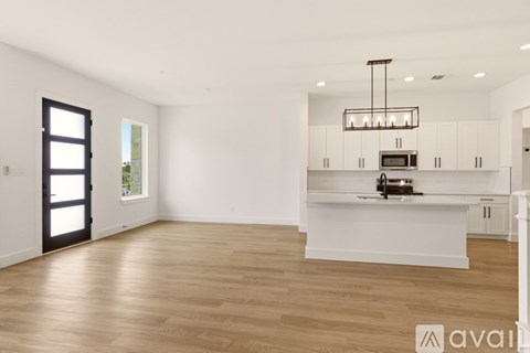 A spacious kitchen with white cabinets and a wooden floor.