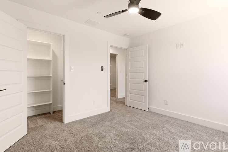 A spacious room with a ceiling fan and two doors.