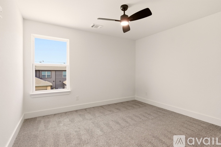 A room with a ceiling fan and a window showing a building outside.