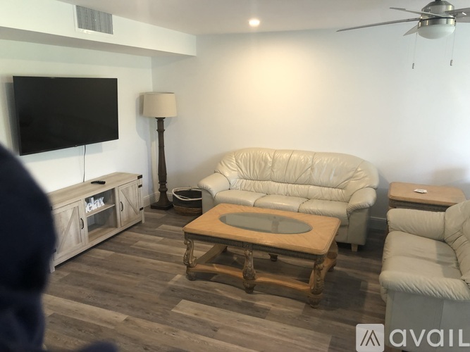 A living room with a white couch, a wooden coffee table, and a flat screen TV mounted on the wall.