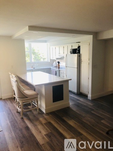 A kitchen with a white fridge and wooden floors.
