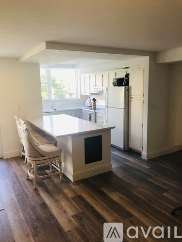 A kitchen with a white fridge and wooden floors.