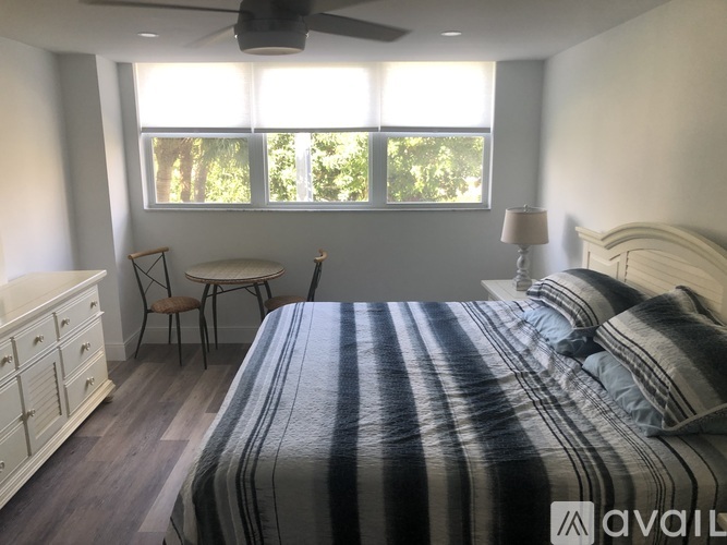 A bedroom with a bed, chair, and window.