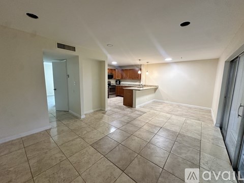 A spacious living room with a kitchen in the background.