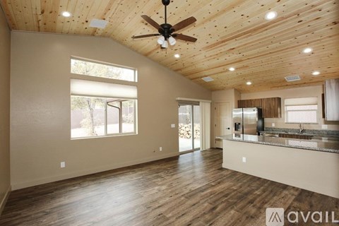 A spacious room with wooden floors and a ceiling fan.