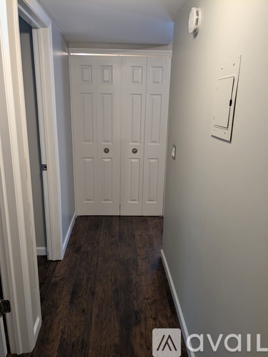 A hallway with a door on the left and a wall on the right.