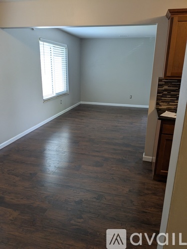 A room with wooden flooring and a window with blinds.