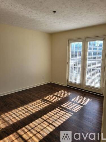 A room with a wooden floor and a window with blinds.