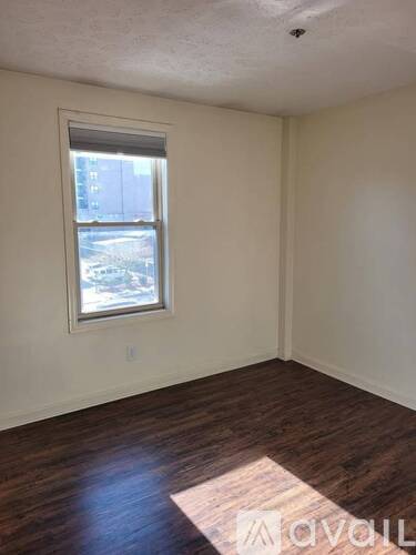 A room with a window and wooden flooring.