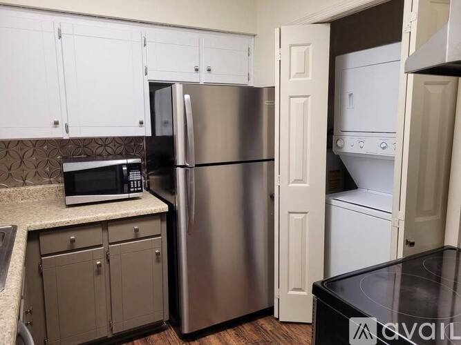 A kitchen with a stainless steel refrigerator and white cabinets.