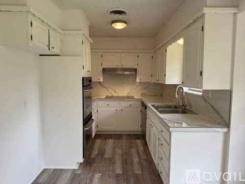 A kitchen with white cabinets and a white refrigerator.