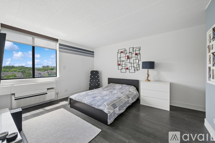 A bedroom with a large bed, a window with a view, and a lamp on a side table.