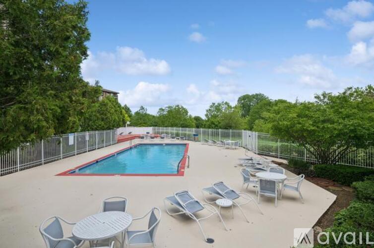 A pool surrounded by chairs and trees.