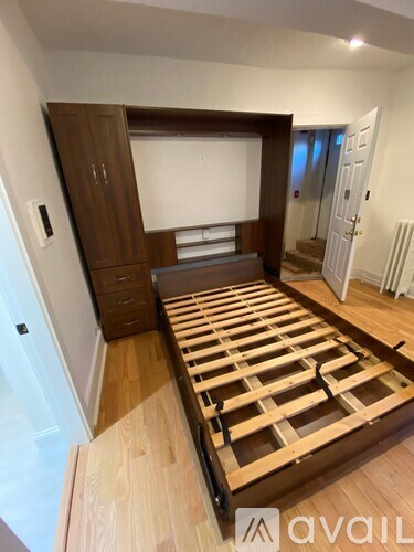 A bedroom with a wooden bed frame and a cabinet in the background.